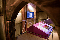 Vitrine in einem Museum, durch einen hölzernen Torbogen betrachtet.