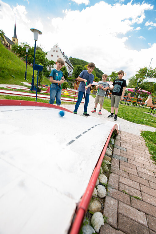 Eine Station der Minigolfanlage mit spielenden Kindern