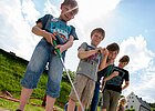 Station der Minigolfanlage mit spielenden Kindern im Vordergrund, ein Kind schiebt gerade den Ball ins Loch