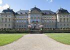 Barocke Schlossanlage mit breitem Weg in der Mitte Richtung Eingang und grünem Rasen beidseits