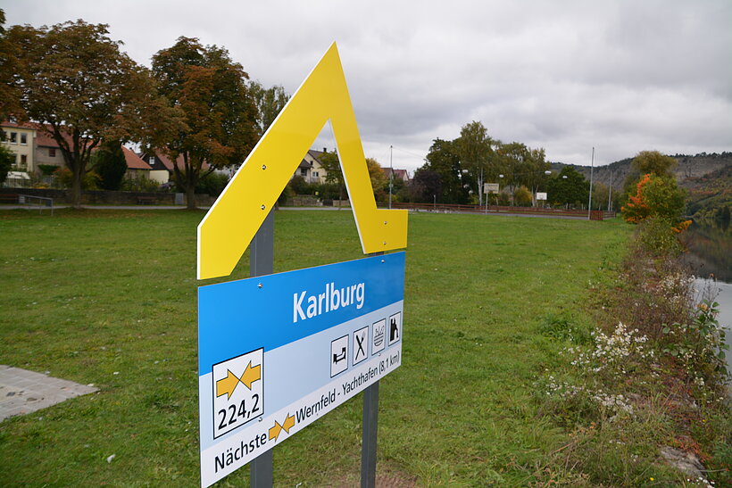 Gelbe Welle in Karlstadt Symbol für Anlegestelle gelb/blau auf grüner Fläche neben Fluss
