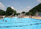 Freibadszene mit schwimmenden und spielenden Besuchern in und am Wasser