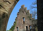 Blick durch Steinbogen auf alte Burgruine mit Giebelseite