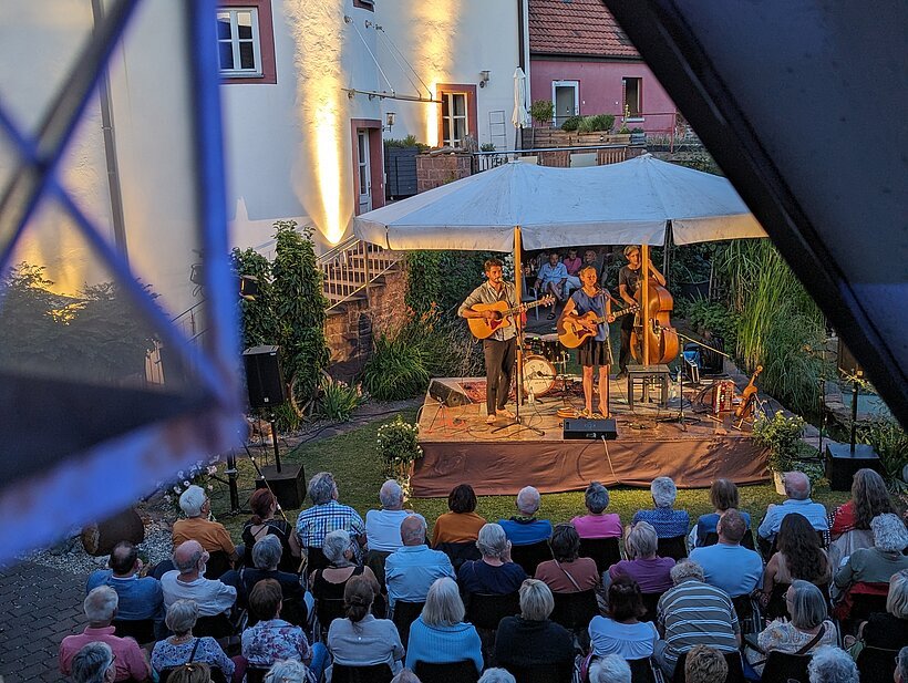 Eine Band spielt auf einer kleinen Bühne vor Publikum