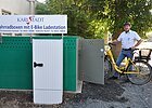 Fahrradboxen in Karlstadt Grüne Boxen zum Einschließen von Fahrrädern, Mann mit gelbem Rad daneben