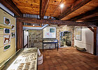 Innenraum mit Holzdecke und Holzboden und präsentierten Ausstellungsstücken an der linken Wand