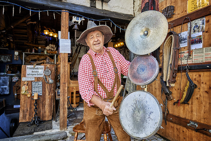 Kleines Bauernmuseum Geldersheim Raum mit Utensilien, drei großen runden Scheiben aus Metall und Mann mit Schlapphut, der sie schlägt